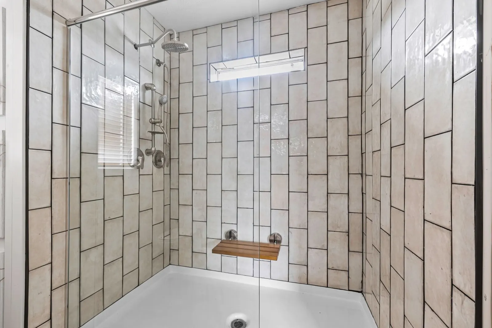 Walk-in tiled shower with rain head and teak bench