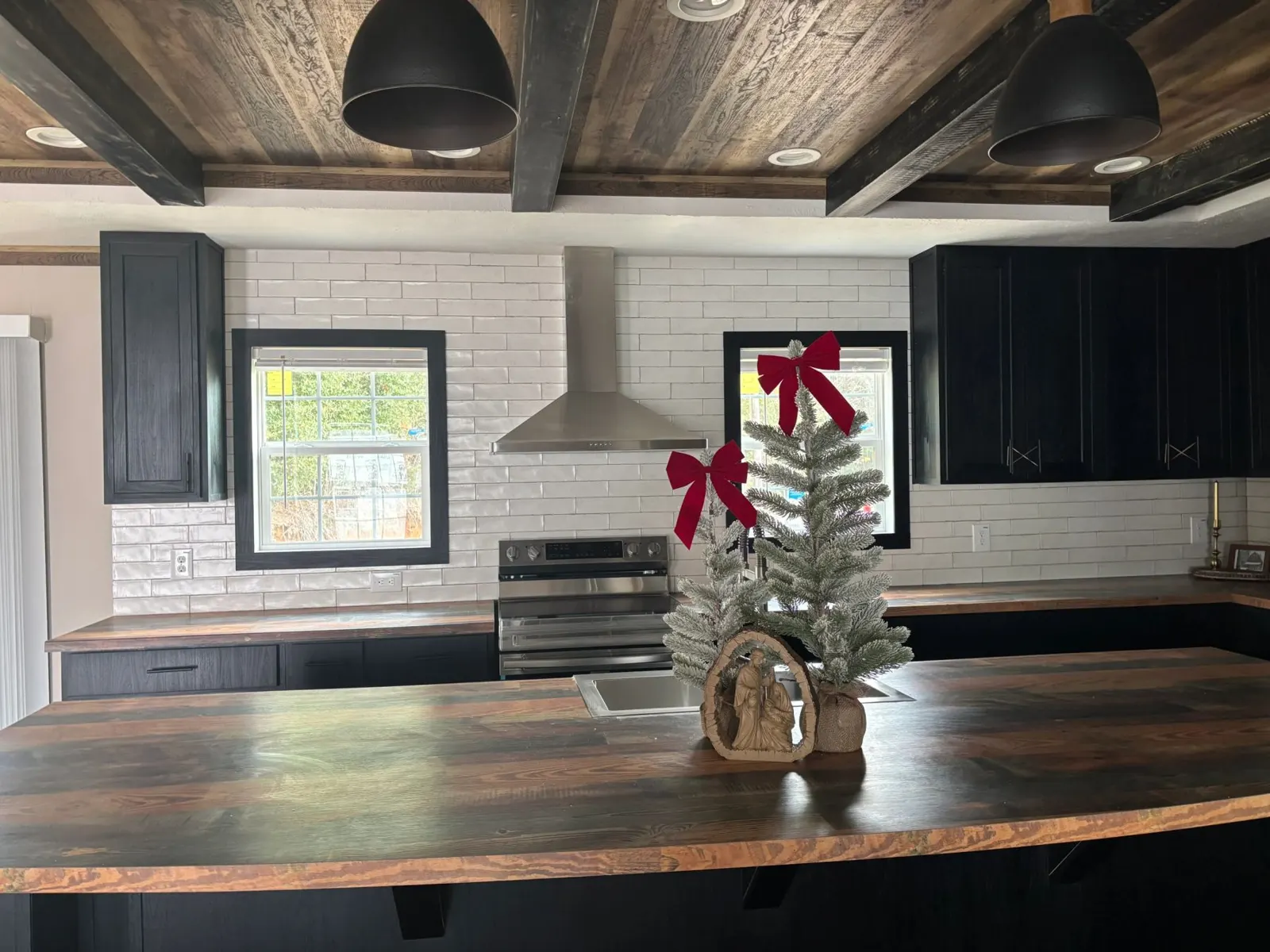Kitchen with dark cabinets, white subway tile and rustic wood beam ceiling