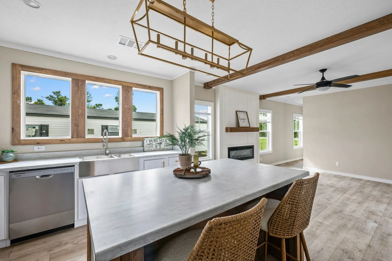 Bright kitchen with a large island, brass lantern pendant and wood-trimmed windows